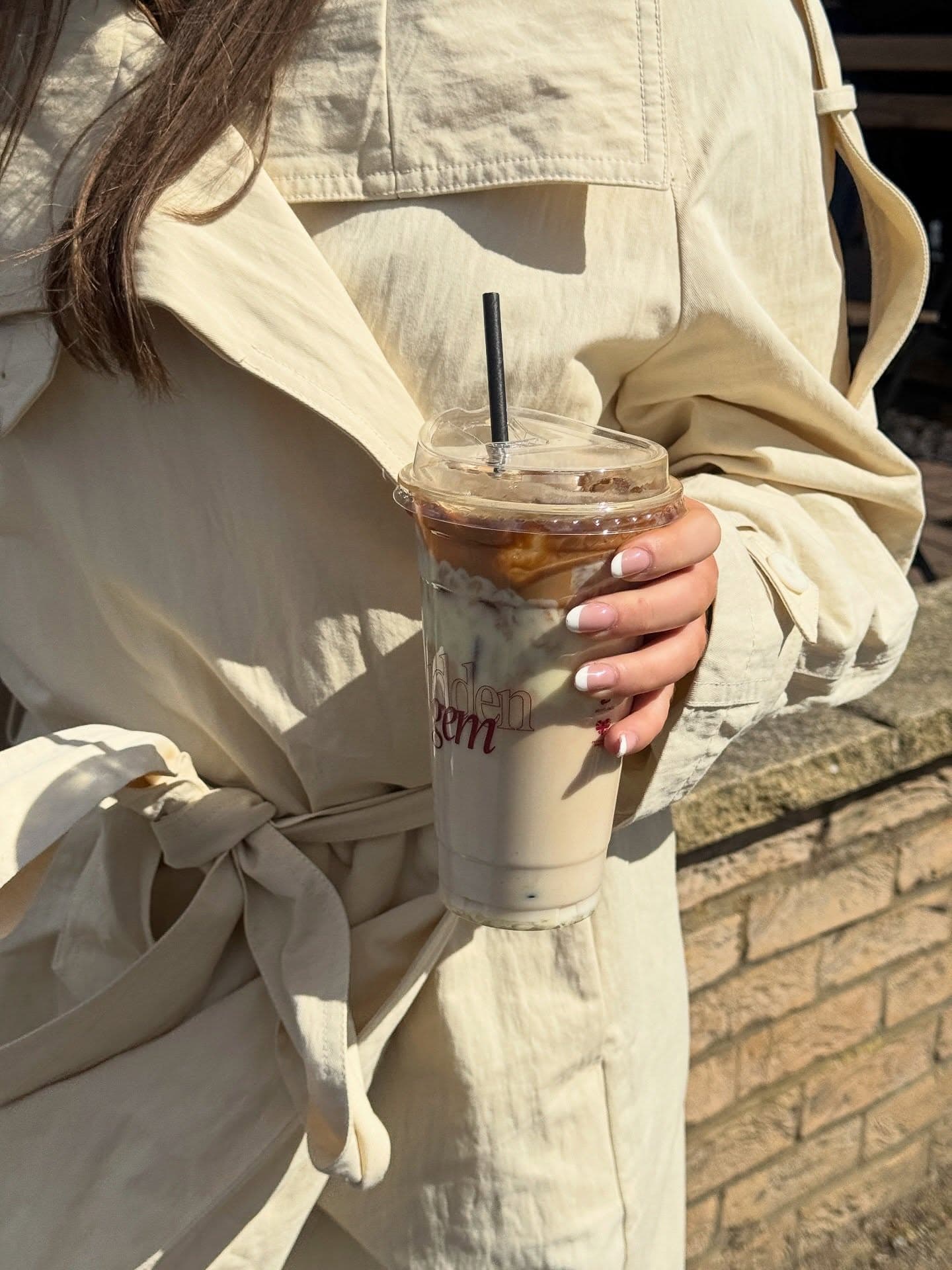 A customer holding an iced latte