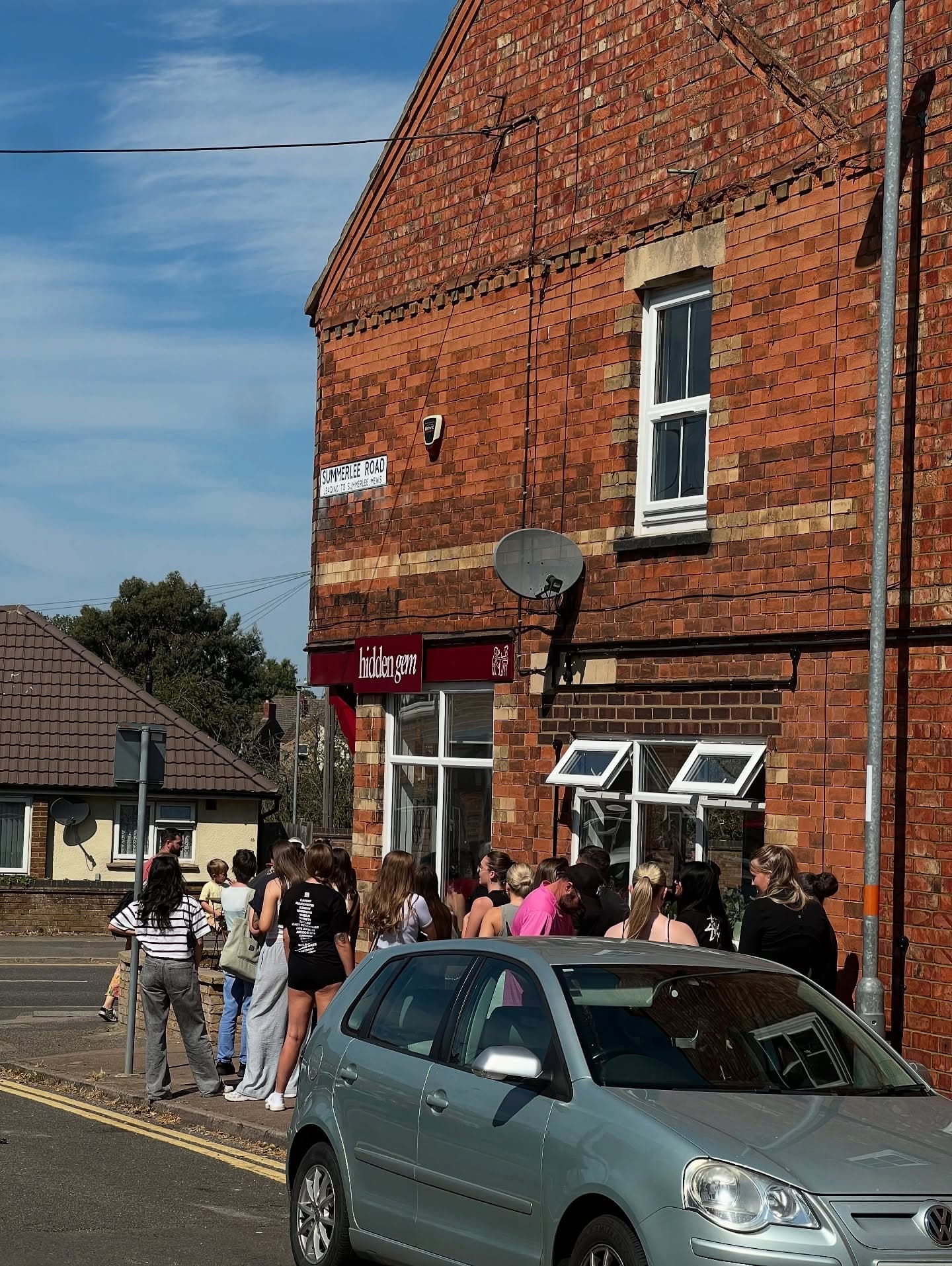 A queue of people outside Hidden Gem on Wellingborough Road on a sunny Saturday